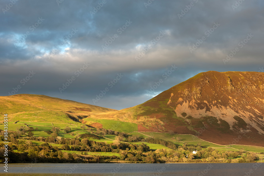 Beautiful landscape image in the English Lake District with glorious Summer sunset light dappled acros the hills
