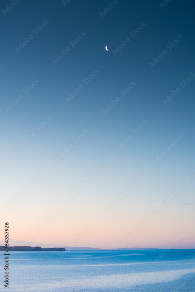 Moon over the Atlantic Ocean with purple sky and mountains in the background Moon over the Atlantic Ocean with purple sky and mountains in the background