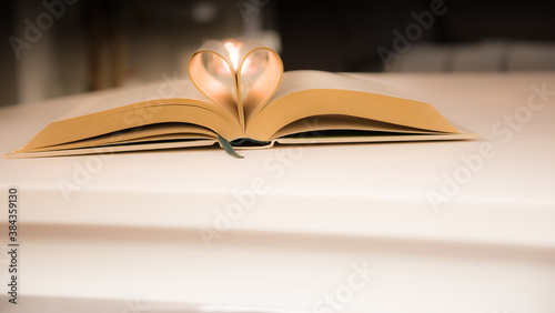 The old book opens, and the book page rolls into the heart colorful background selective focus and shallow depth of field