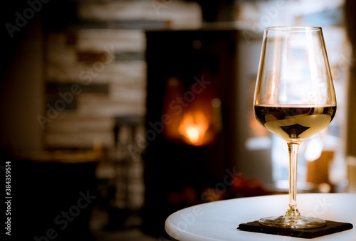 Cozy winter scene. Red wine with a fire in a fireplace in the background.