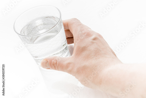 Man hand isolated holding a glass of water on bright white background.