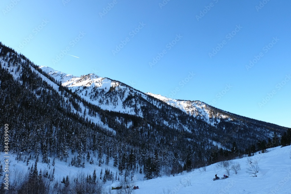 Winter mountain landscape at Baikal. Khamar-Daban ridge. Snow-capped peaks, chalets in the mountains. Winter forest.