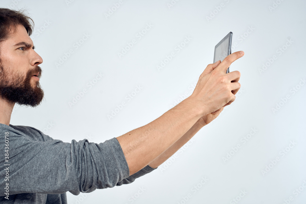 A man with a tablet in his hand internet technology communication gray jacket light background