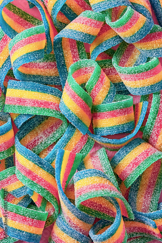Colorful sugar candy ribbon on a pink background viewed from above. Top view. Full frame