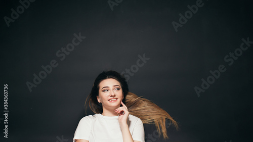 beautiful young woman with long hair lying on black studio background, happy student girl top view