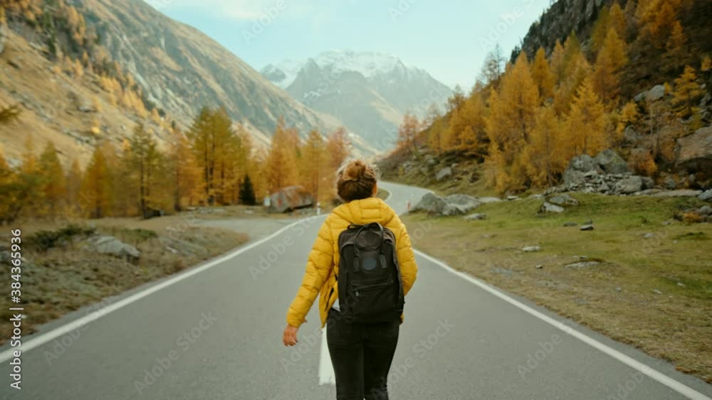 Camera follows woman on trip or adventure. Young millennial traveller or travel blogger walk in beautiful mountain valley and make photos for social media or memories. Generation z new concept travels