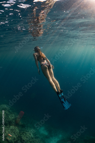 A female freediver is exploring a tropical coral reef.