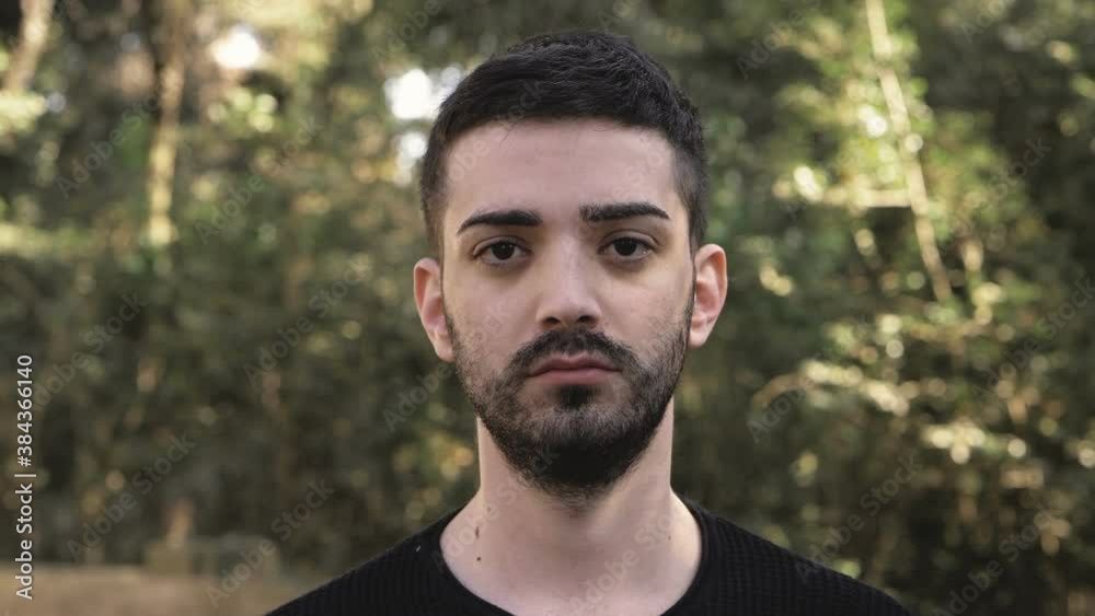 young pensive man looking at camera blinking and smiling - outdoor young pensive man looking at camera blinking and smiling - outdoor