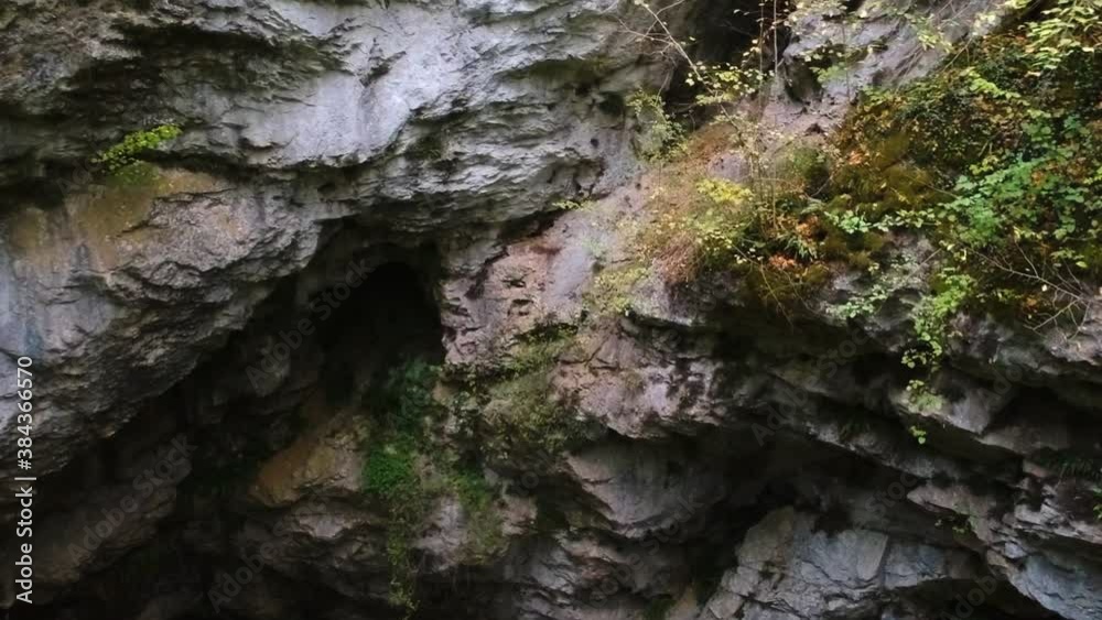 Cave entrance surrounded by stone-walled ledges and small bushes. Cave entrance surrounded by stone-walled ledges and small bushes.