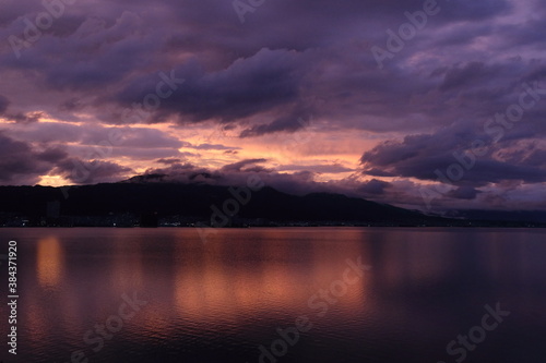 紫に染まった雲とオレンジを反射した水面 © MaP