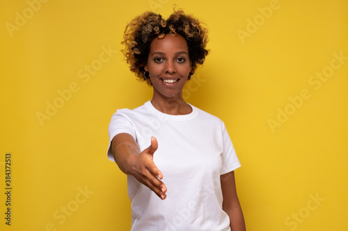 Young beautiful affrican woman smiling friendly offering handshake as greeting and welcoming. photo