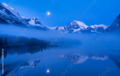 Blue Light and Lake Mirror of Moon, Clouds and Mountains of Glacier National Park © Andy