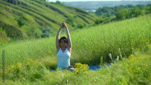 Young woman doing yoga in green summer meadow