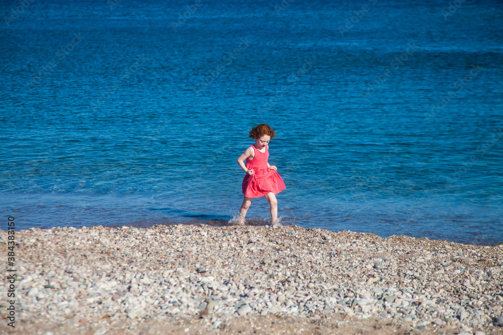 Cute redhead girl walking the shore