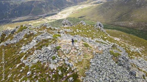Aerial Circular view of a Male Alpinist and Climber in the Summit of a Mountain with impressive rocky views. Fitness, Sport and Healthy Life. Asturias, Spain
