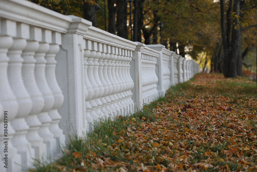 Stone balustrade long row on the colorful background of the autumn Park.Selective focus.Close-up of the Baroque style.Background texture. Stone balustrade long row on the colorful background of the autumn Park.Selective focus.Close-up of the Baroque style.Background texture.