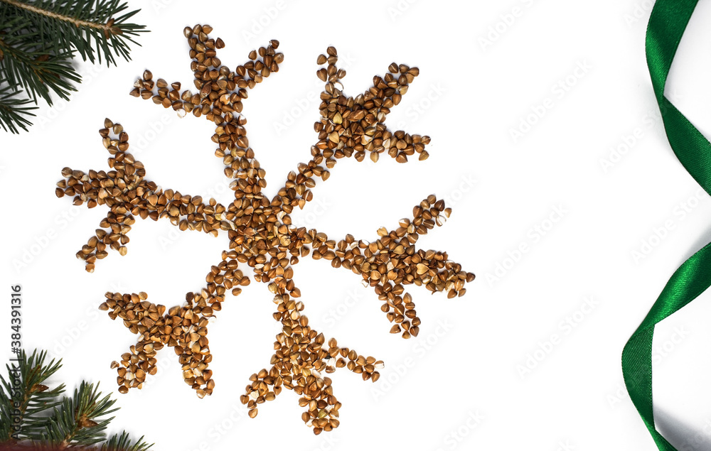 On a white background on the left a snowflake of buckwheat among spruce branches and a green ribbon with a space for text on the right