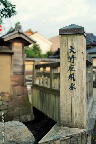 Japanese text is " Ohno canal river". Japanese wood bridge over irrigation canal in old town at Kanazawa Japan.