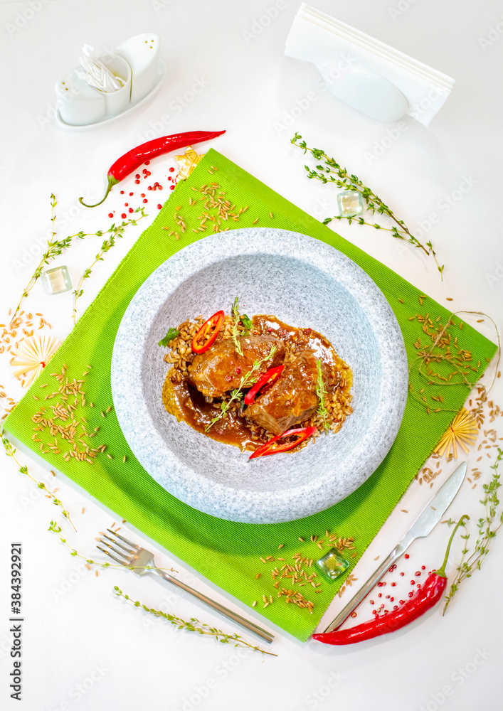 Stewed beef cheeks with spelled in a marble gray plate on a green tablecloth. Decor. Top view. Selective focus. Super short focus Stewed beef cheeks with spelled in a marble gray plate on a green tablecloth. Decor. Top view. Selective focus. Super short focus