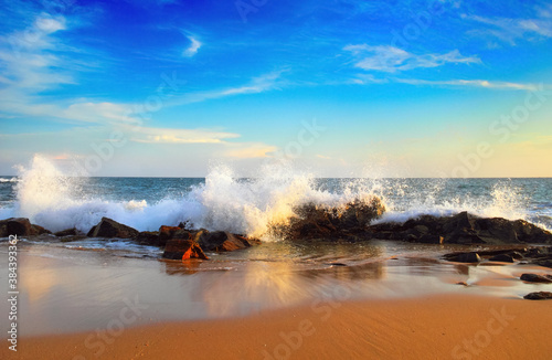 Beautiful scenic view of the wild rocky coast with dramatic surf water of Indian ocean against the background of cloudy blue sky at sunset time in Tangalla beach, Sri Lanka island, South Asia