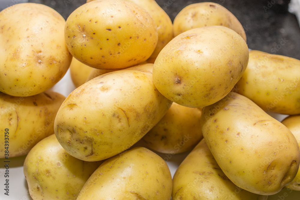 Raw potato washed on a white plate