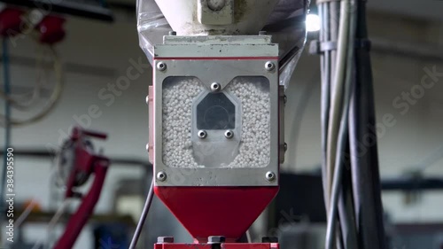 The accumulation tank of the industrial injection molding machine-extruder. In the square inspection window, polypropylene granules are visible