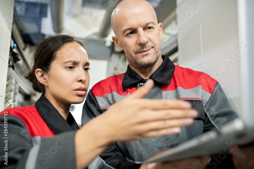 Young female subordinate pointing at laptop display during presentation