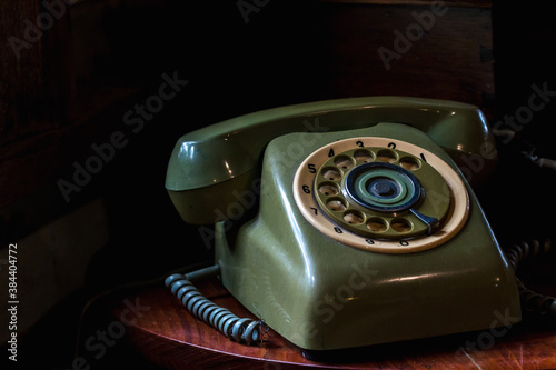 Old telephone on wooden table on black background