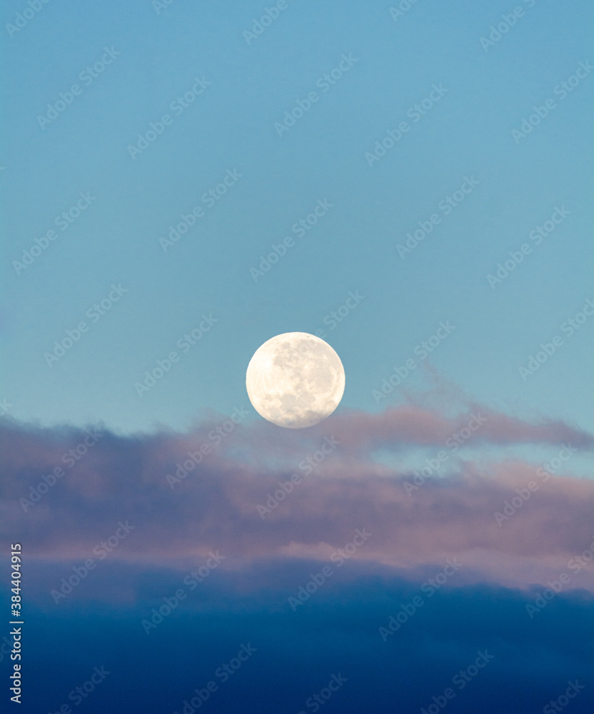 full moon in a blue sky with clouds