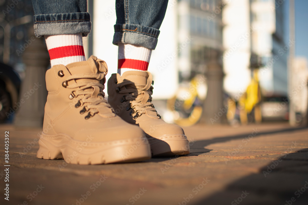 a young girl in winter boots is standing on the sidewalk. stylish beige winter boots.
