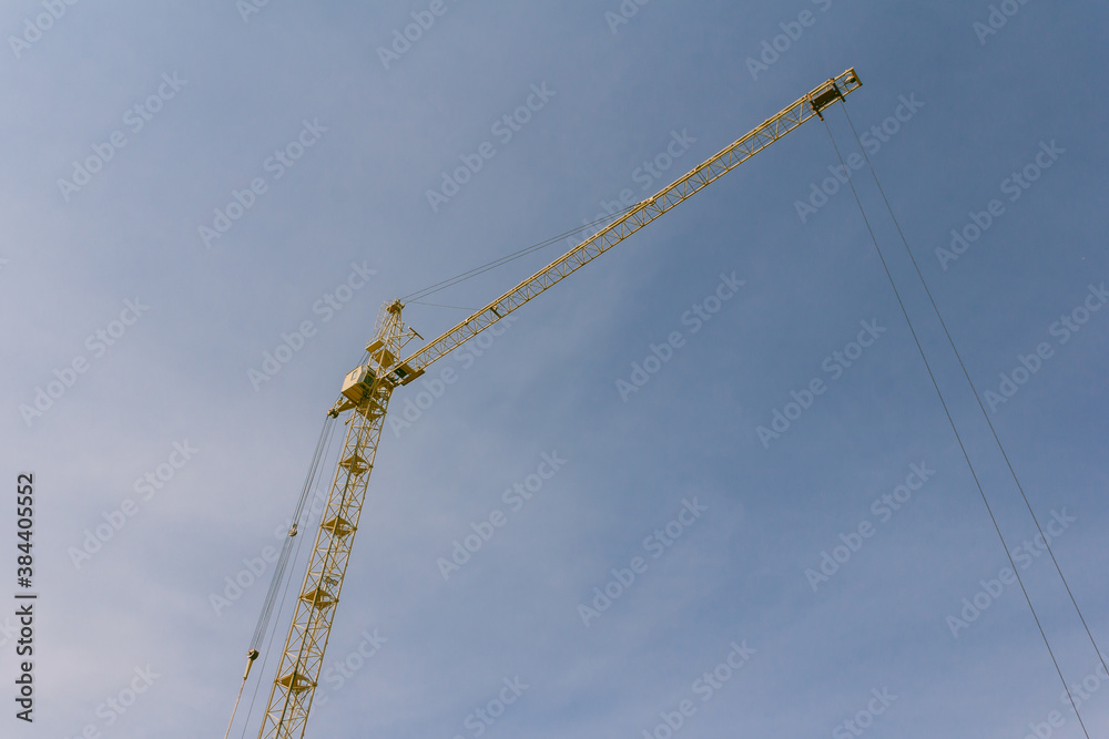 Construction crane on a background of blue sky. Equipment for lifting heavy loads on a construction site. Construction crane on a background of blue sky. Equipment for lifting heavy loads on a construction site.