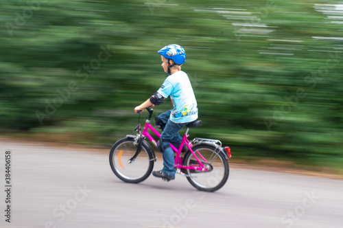 Junge auf rotem Fahrrad mit blauem Helm vor grünem Hintergrund © reliant_de