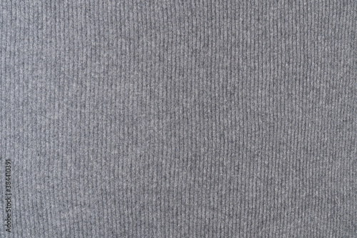 Background texture of grey knitted fabric made of wool with vertical stripes.