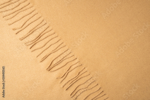 Beige wool fabric with fringe for background.