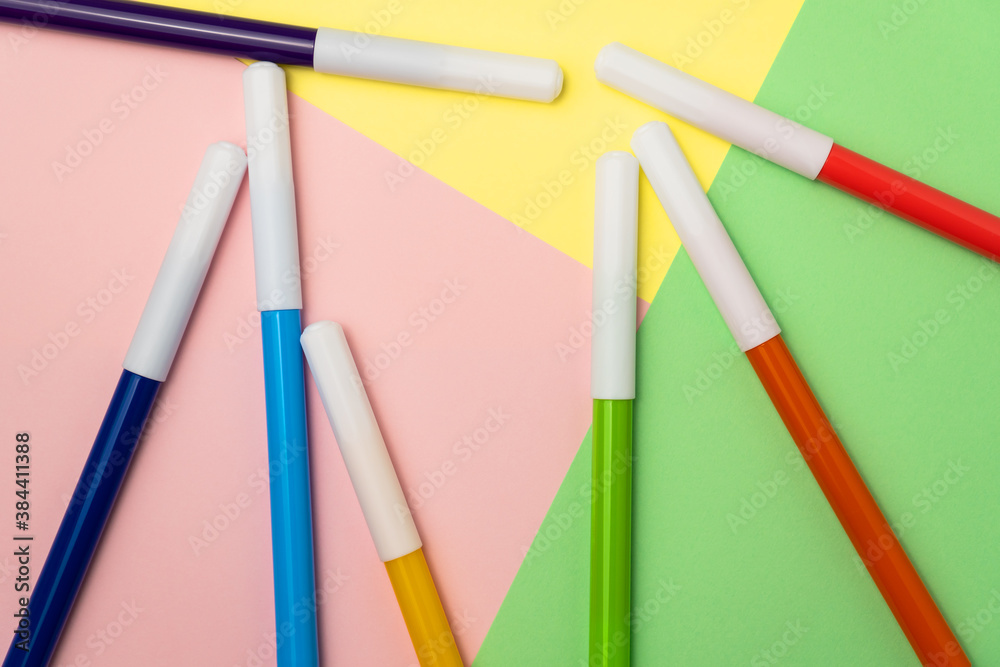 Multicolored felt-tip pens on background of colored paper.