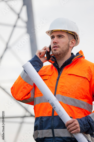 Young engineer talking on smart phone in front of an oil rig or construction site