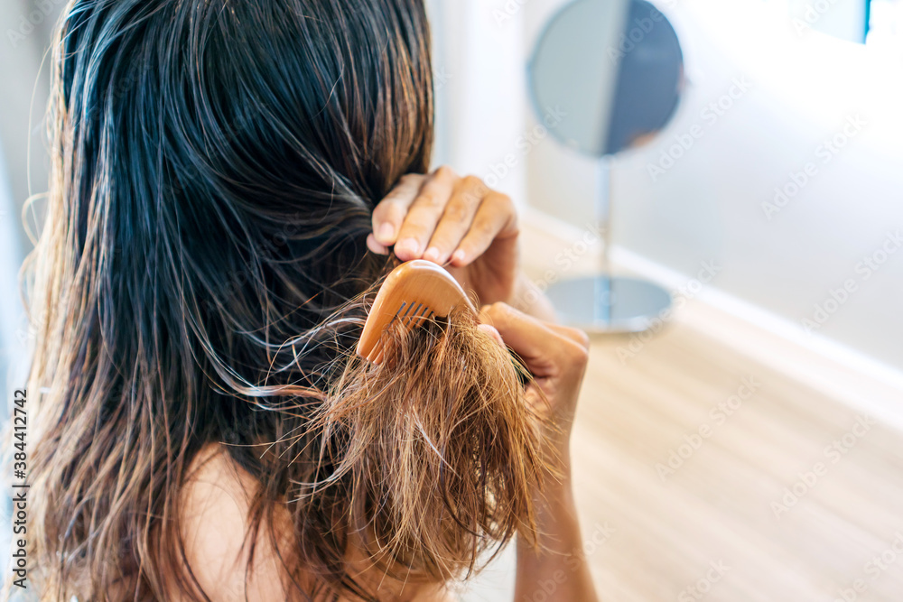 Close up of sad young Asian woman brush her damaged and tangled wet hair.  Stock Photo | Adobe Stock