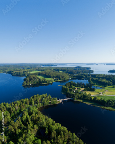 Aerial view on the bridge over the lake. Blue lakes, islands and green forests from above on a sunny summer morning. Lake landscape in Finland, Paijanne.
