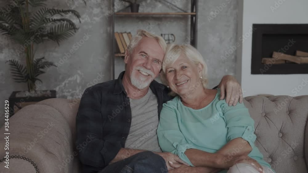 Affectionate attractive elderly couple sitting together and kissing on a couch Affectionate attractive elderly couple sitting together and kissing on a couch