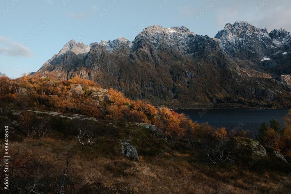 Naklejka premium Uninhabited Lofoten Islands during Covid-19 pandemic situation in autumn. No tourists and very quiet and peaceful fall mood. View into fjord with spectacular mountains with fresh snow around. 