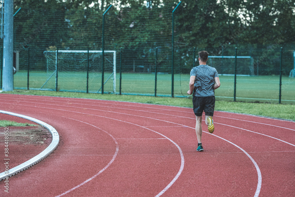 Young Caucasian man in a swing running pose, with feet in the air, from behind