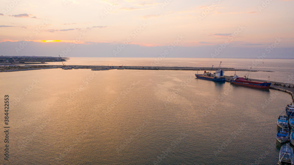 Beautiful panoramic aerial view photo from flying drone on Molfetta port lighthouse. In the backgroundport with ships, waterfront, yachtsand and Molfetta city at sunset.Apulia,Italy (Series)
