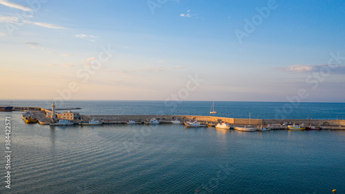 Beautiful panoramic aerial view photo from flying drone on Molfetta port lighthouse. In the backgroundport with ships, waterfront, yachtsand and Molfetta city at sunset.Apulia,Italy (Series) photo