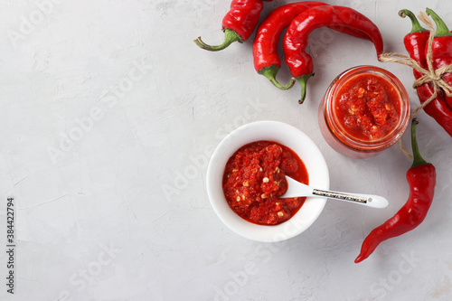 Traditional sauce adjika with hot chili pepper, paste harissa on light background. Horizontal orientation. Top view