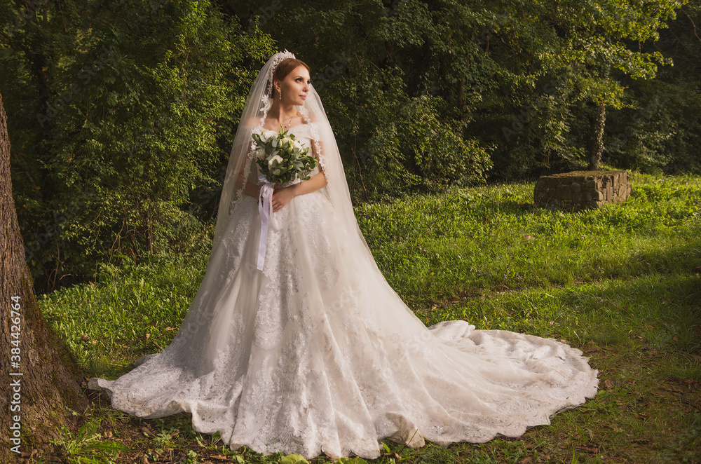 bride in a wedding dress with a long train and a bouquet against the background of ancient walls and nature bride in a wedding dress with a long train and a bouquet against the background of ancient walls and nature