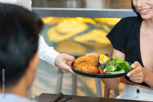 Waitress serve healthy food to caucasian customer smiling and sitting.