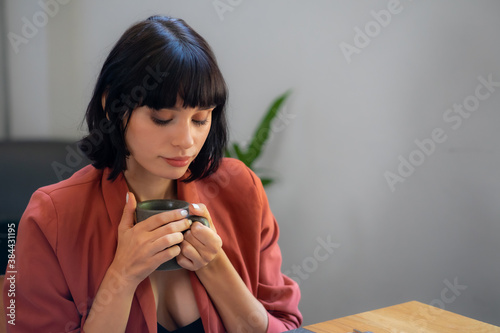 Closeup portrait caucasian lady holding, smelling coffee and smile.