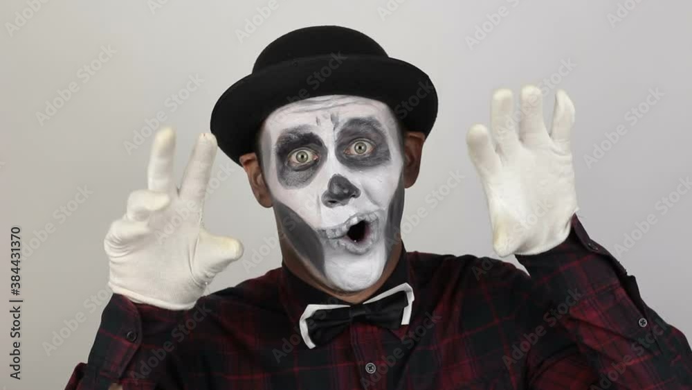 A horrible man in clown makeup grimaces and makes frightening gestures. A scary clown looks at the camera and laughs terribly. Scary grimaces of a clown looking at the camera. Halloween costume. A horrible man in clown makeup grimaces and makes frightening gestures. A scary clown looks at the camera and laughs terribly. Scary grimaces of a clown looking at the camera. Halloween costume.