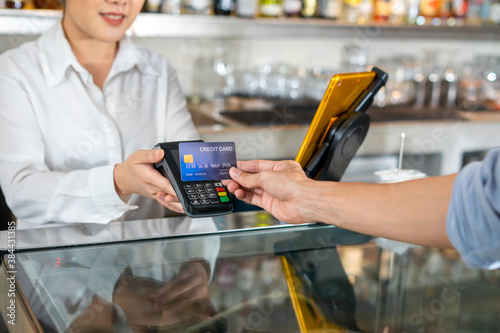 Customer use wireless credit card with EDC at cashier in restaurant.
