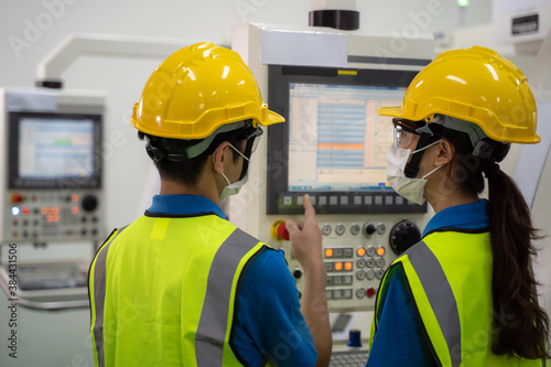 Male and female engineers discuss operating process on machine screen.